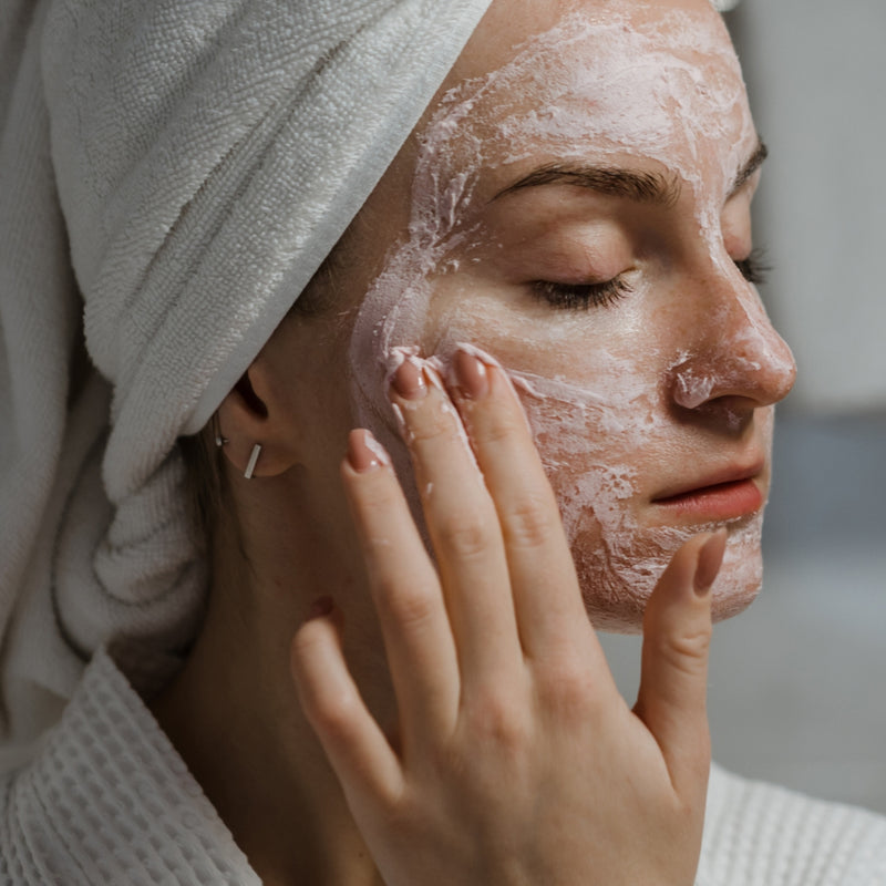 Woman applying facial mask with a towel on her head
