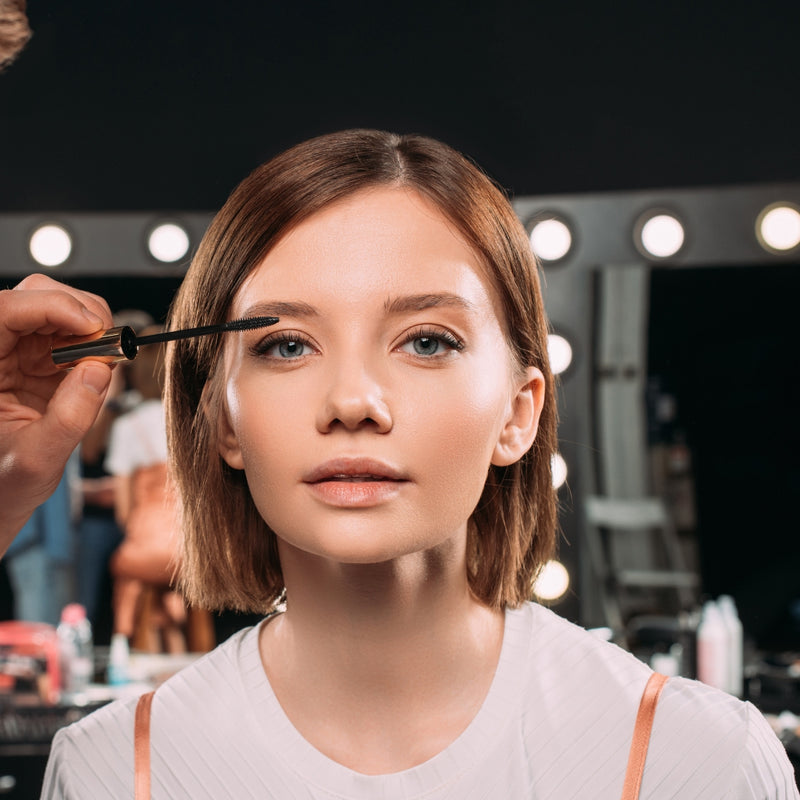 Woman getting makeup applied with a brush in a salon setting